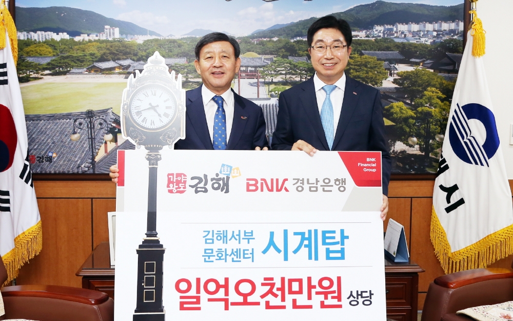 황윤철 BNK경남은행장(사진 오른쪽)이 김해시 허성곤 시장에게 ‘(재)김해서부문화센터 시계탑 기증서’를 전달한 뒤 기념촬영하고 있다. / 사진= BNK경남은행