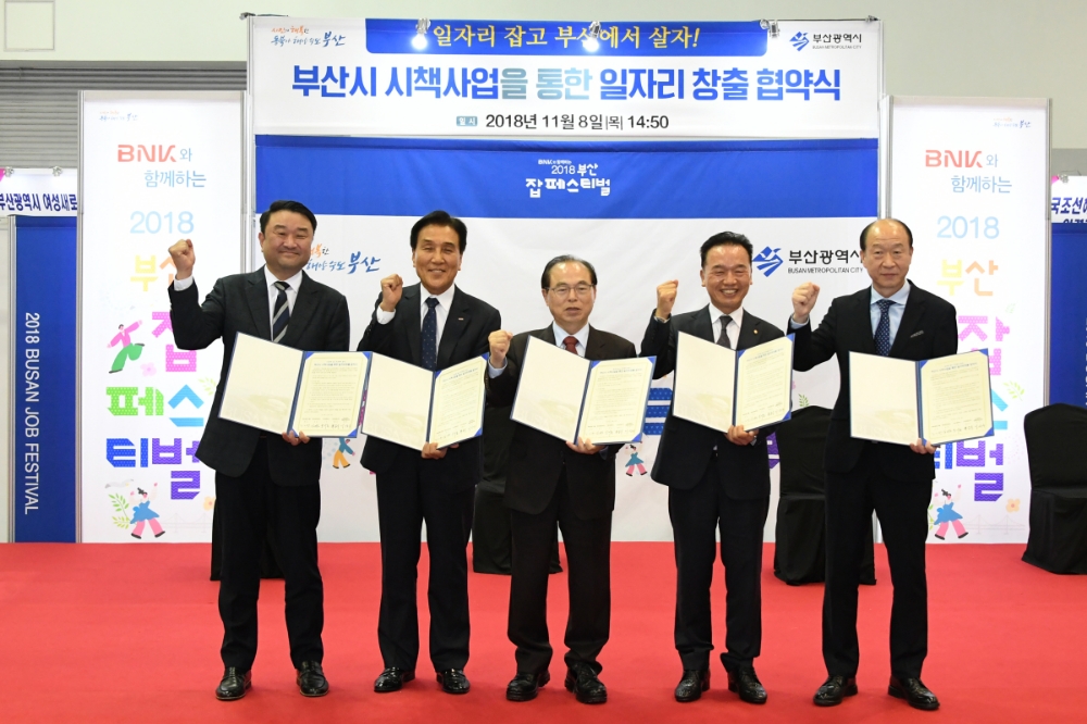 BNK금융그룹이 8일 부산 벡스코에서 부산시와 공동으로 주최한 ‘BNK와 함께하는 2018 부산 잡(Job) 페스티벌’에서 일자리창출 업무협약을 체결한 모습. (사진 왼쪽부터) 동의과학대학교 김영도 총장, BNK금융그룹 김지완 회장, 부산광역시 오거돈 시장, 선보공업 최금식 회장, 부산시 맞춤훈련협의회 이상우 회장. / 사진제공= BNK금융지주