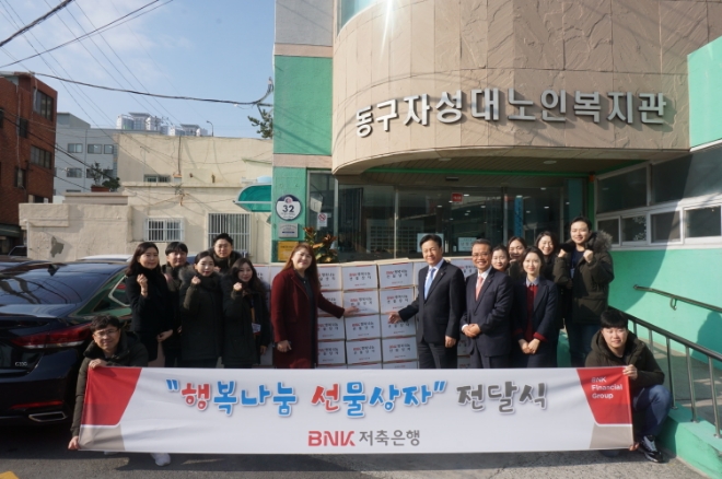 지난 21일 성명환 BNK저축은행 대표(사진 중앙 오른쪽)와 임직원들이 부산 자성대노인복지관을 방문해 생필품 등을 담은 ‘행복나눔 선물상자’ 100개를 전달했다. / 사진 = BNK금융지주