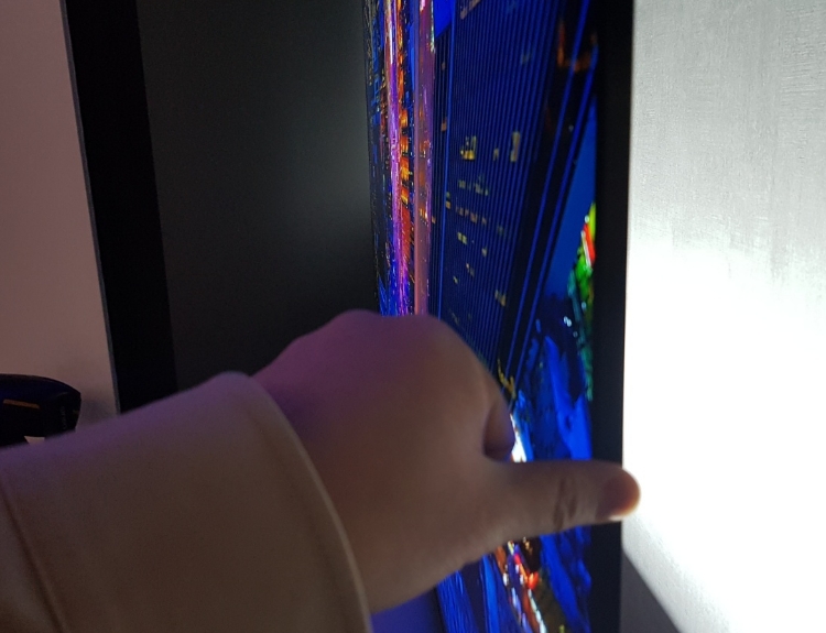 △88인치 시그니처 K 제품이 얼마나 얇은지 확인하기 위해 기자가 왼손 엄지 손가락을 옆면에 대고 촬영한 모습/사진=오승혁 기자