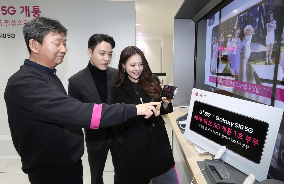 △서울 종로직영점에서 황현식 LG유플러스 PS부문장 부사장(사진 왼쪽)과 LG유플러스 갤럭시 S10 5G 1호 고객인 모델 겸 방송인 김민영 씨(여, 29세), 카레이서 서주원 씨(남, 26세) 부부가 개통이 완료된 5G스마트폰으로 U+5G 핵심 서비스를 체험하고 있는 모습/사진=LG유플러스