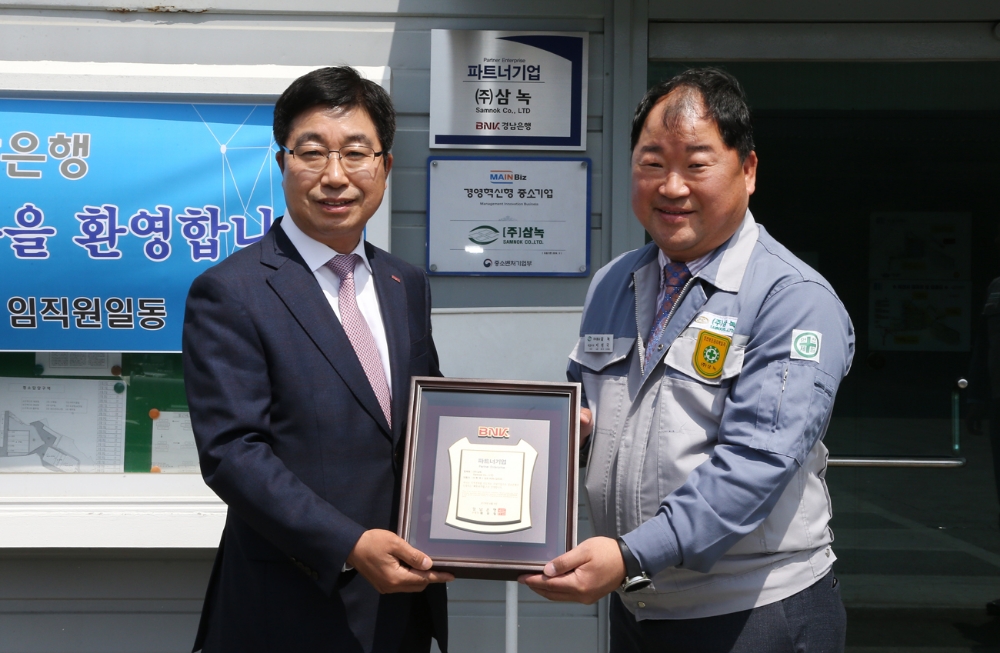 BNK경남은행 황윤철 은행장(사진 왼쪽)이 ㈜삼녹 이헌국 대표이사에게 파트너기업 인증패를 전달하고 있다./사진=경남은행