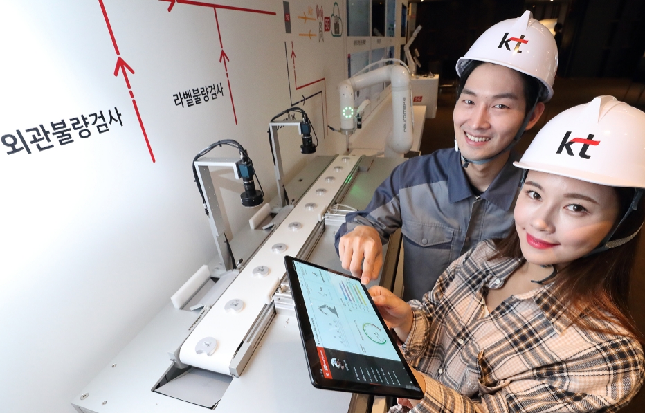 △KT 모델들이 5G 스마트팩토리 상품을 보여주는 미니 제조 공정라인을 소개하고 있으며, 스마트패드를 통해 실시간으로 공장 내 상황을 확인할 수 있는 점을 시연하고 있다/사진=KT