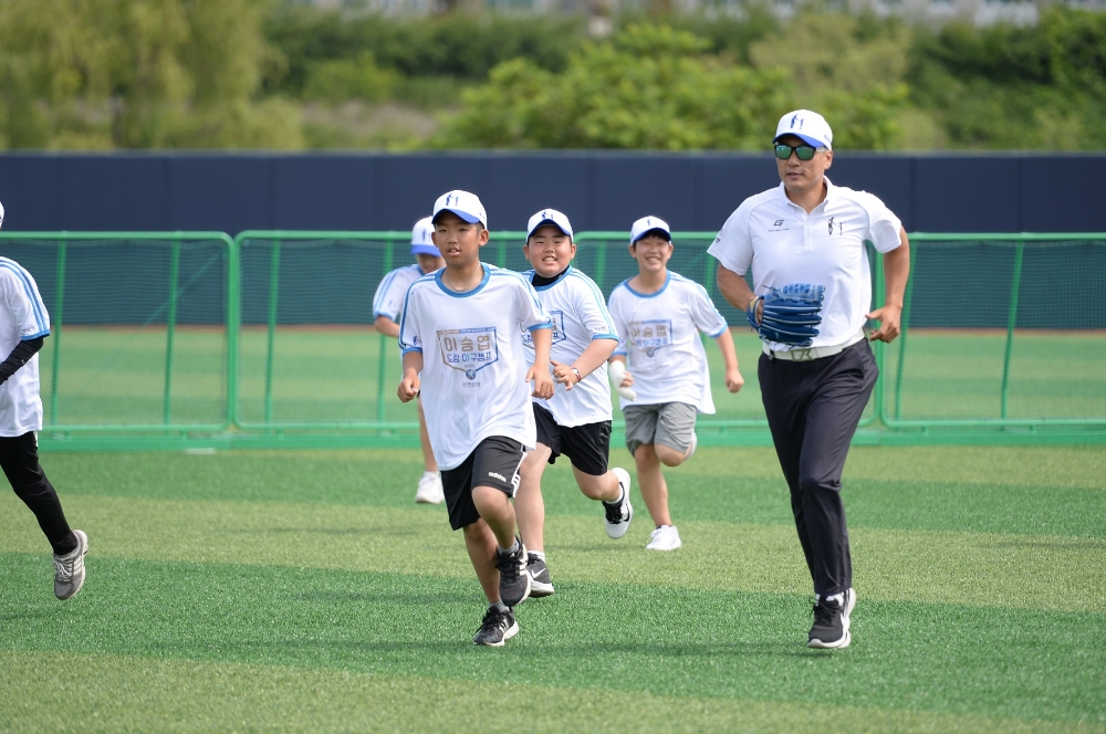 신한은행이 지난 13일 강릉 남대천체육공원 야구장에서 ‘이승엽 야구장학재단’과 함께 개최한 ‘이승엽 Dream 야구캠프 with 신한은행’에서 이승엽 이사장(오른쪽)이 참가한 학생들과 함께 그라운드를 뛰고 있다. / 사진= 신한은행