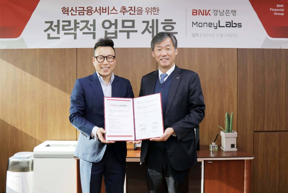 최우형 BNK경남은행 부행장보(사진 오른쪽)가 머니랩스 백인호 부사장과 ‘혁신금융서비스 개발을 위한 업무 협약’을 체결하고 있다./사진=경남은행