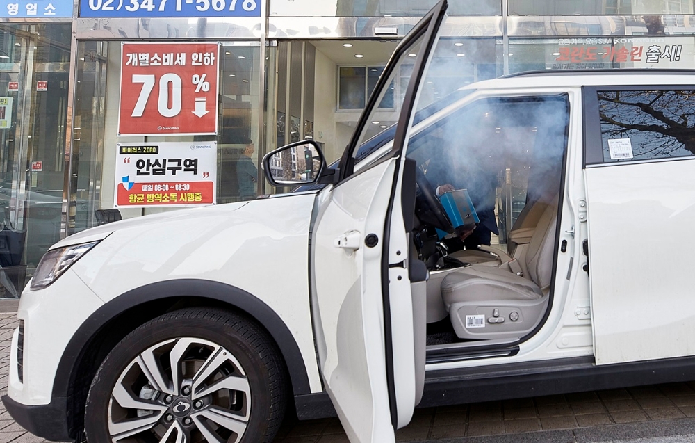 쌍용차 관계자가 전시장 내방객 차량 실내에 연막 소독 서비스를 실시하고 있다. 사진=쌍용차.