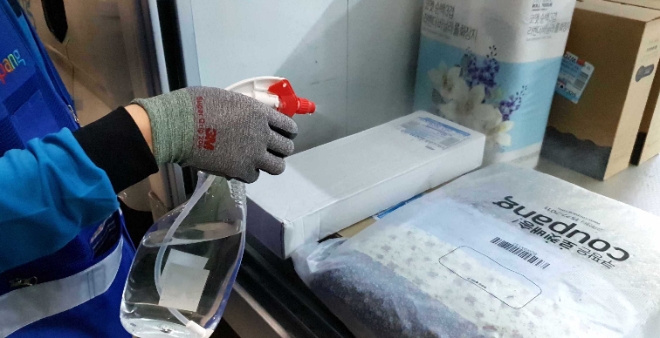 쿠팡맨이 고객에게 로켓배송 상품을 배송하기 직전에 상품을 살균소독하고 있다. / 사진 = 쿠팡