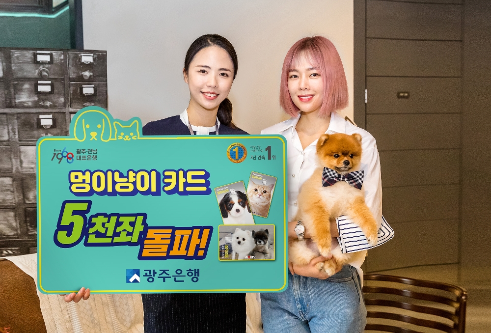 ▲광주은행 '멍이냥이카드'를 이용중이며, 광주은행 본점 인근에서 커피샵 <아카이브>를 운영 중인 배우 한주영(사진 오른쪽, 영화 '상류사회' 민현아 역)이 반려견 '쿠모'와 함께 '멍이냥이카드' 5천좌 돌파 축하 기념 촬영을 하고 있다./ 사진제공 = 광주은행