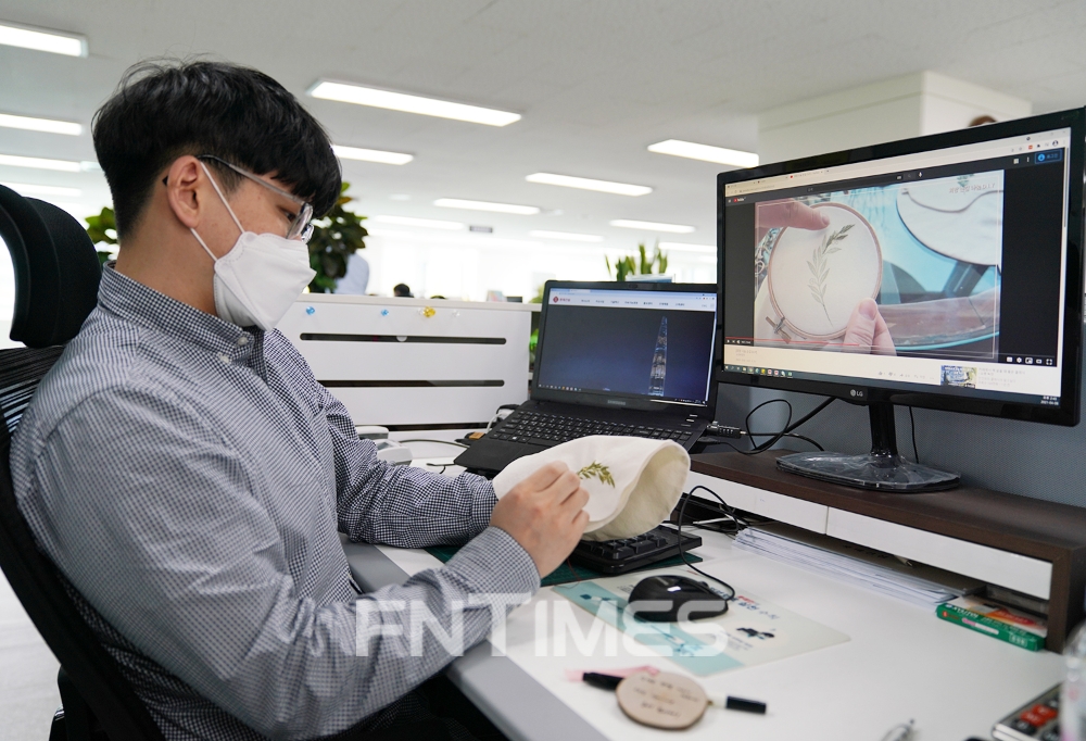 롯데건설 직원이 동영상을 보며 에코 파우치를 만들고 있다. / 사진=롯데건설