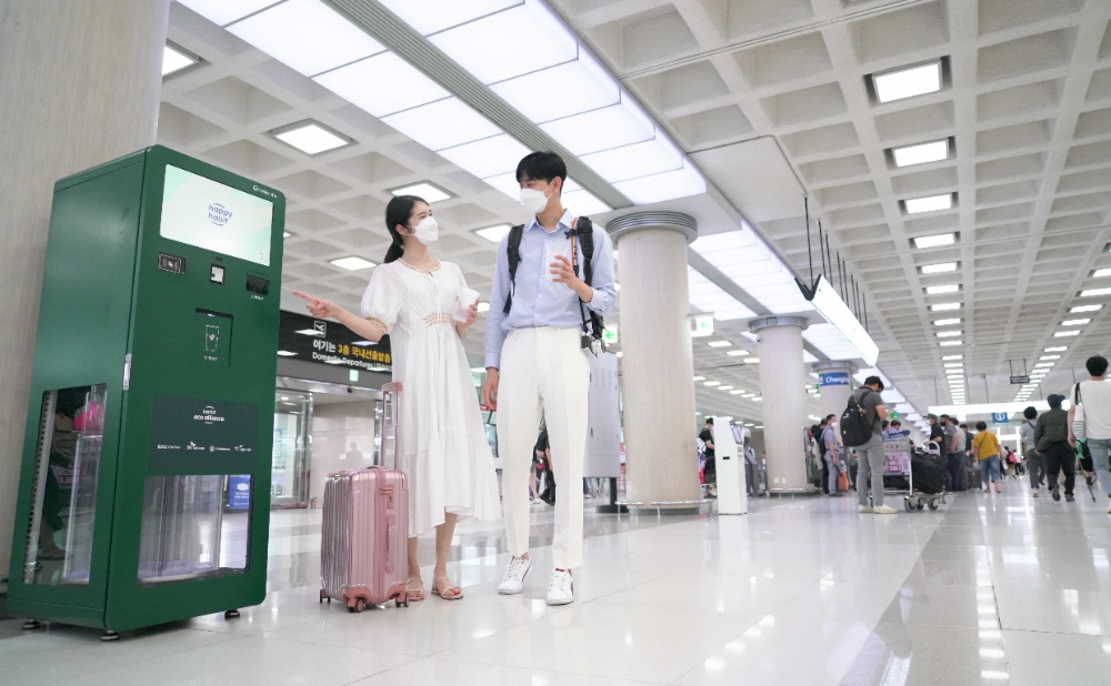 제주 관광객들이 제주국제공항 안에 설치된 무인 다회용컵 반납기를 통해 사용을 마친 컵을 반납하고 있다. 사진=SK텔레콤