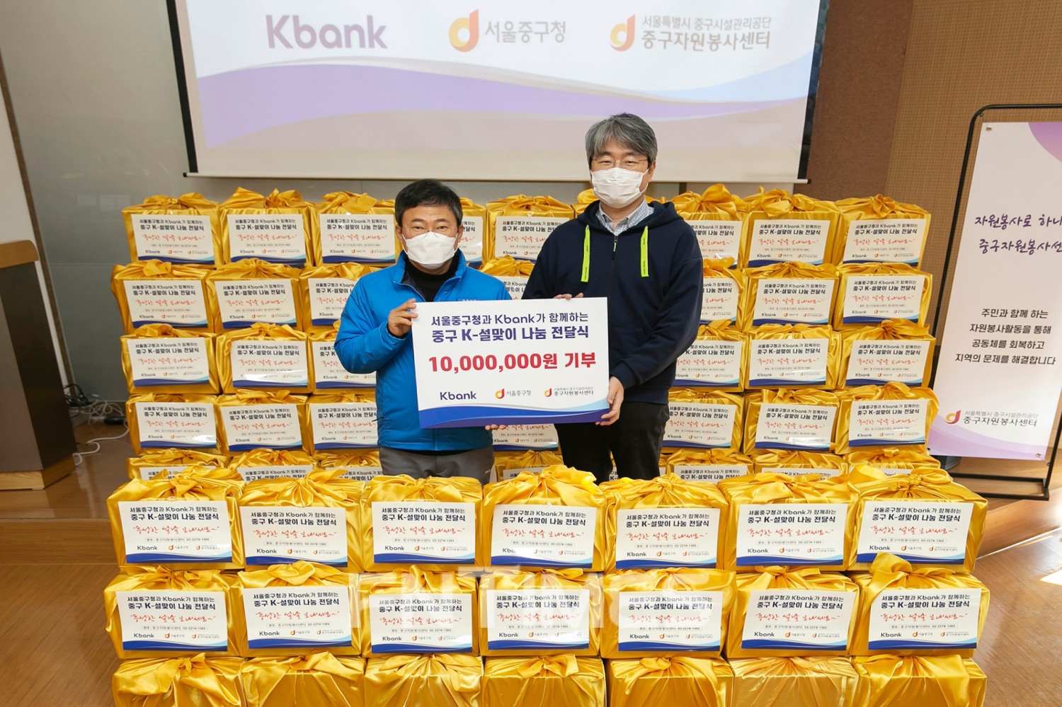 장민 케이뱅크(은행장 서호성) 경영기획본부장(오른쪽)과 서양호 서울시 중구청장이 21일 중구자원봉사센터 강당에서 설맞이 명절 꾸러미 전달식을 진행하고 있다./사진=케이뱅크