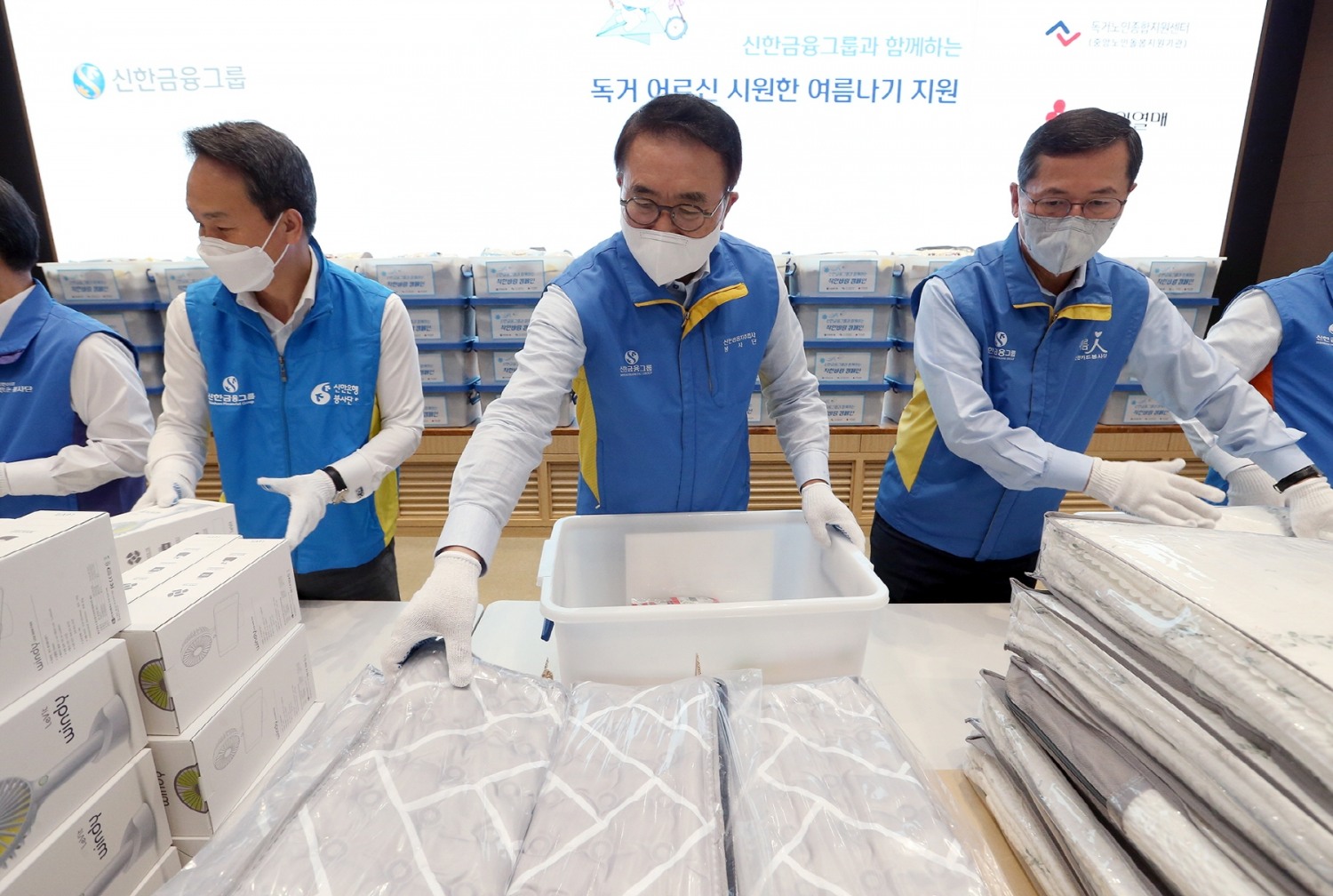 행사에 참여한 신한금융그룹 조용병 회장(사진 가운데)과 신한은행 진옥동 은행장(사진 왼쪽), 신한카드 임영진 사장이이 '독거노인 여름나기 키트'를 제작하는 봉사활동을 하고 있다. / 사진제공=신한금융그룹