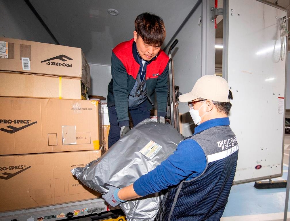 롯데택배 직원과 매일드림 자활사업 참여자가 차량에서 택배물품을 내리고 있다./사진제공=용산구