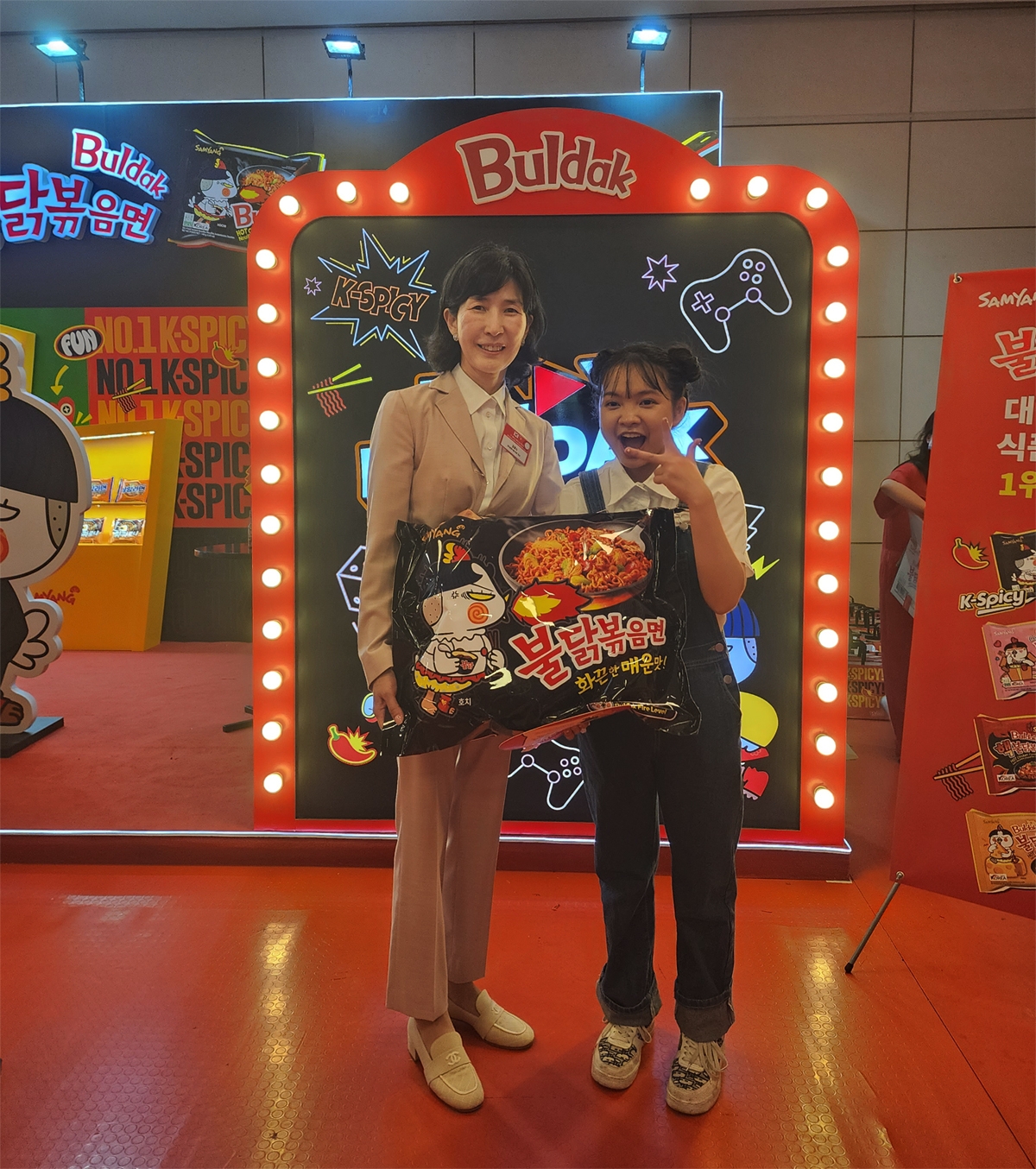 하노이에서 진행된 K-Food 페스티벌 삼양식품 부스 앞에서 삼양식품 김정수 부회장(왼쪽)과 베트남 인플루언서 자한(N.ZaHan)이 사진을 촬영하고 있다./ 사진 = 삼양식품