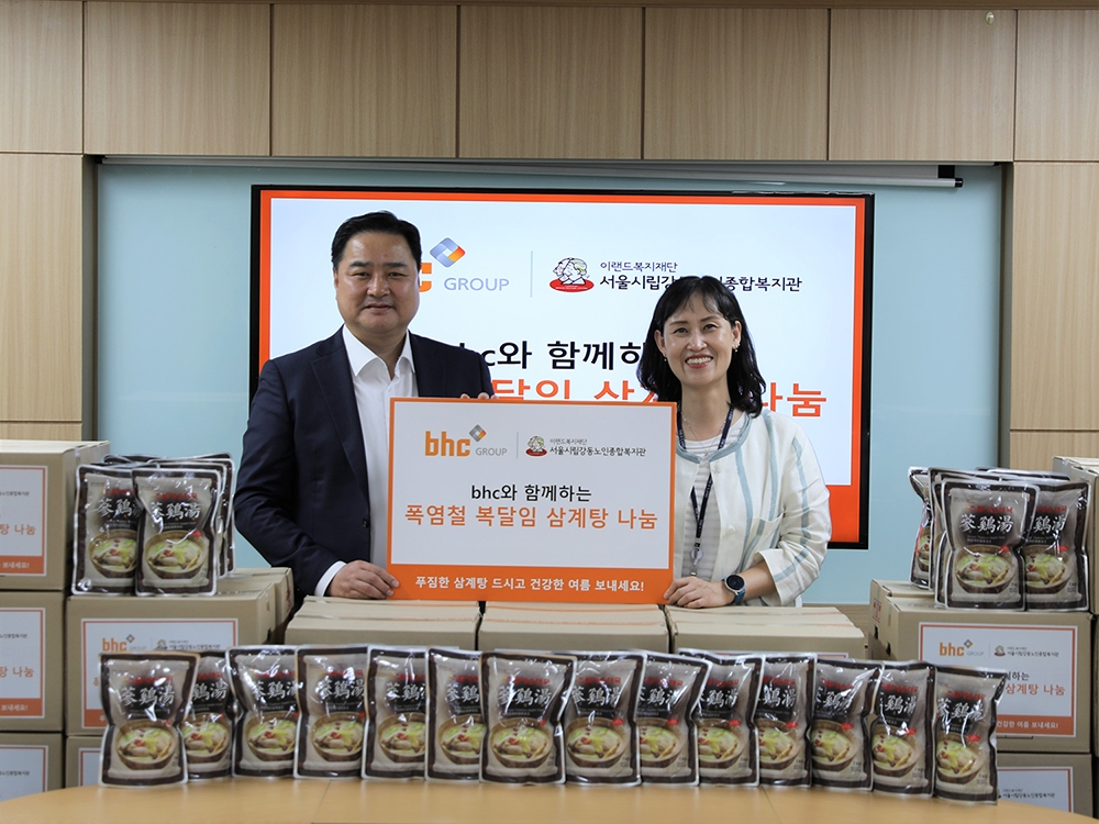 bhc그룹 임인엽 이사(좌측)가 서울시립 강동노인종합복지관 성미선 관장(우측)에게 삼계탕을 전달한 후 기념촬영을 하고 있다./ 사진 = bhc그룹