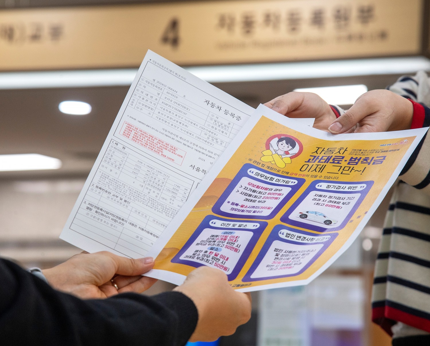 용산구청 담당자가 민원인에게 자동차등록증과 자동차 과태료 범칙금 안내문을 함께 전달하고 있다./사진제공=용산구