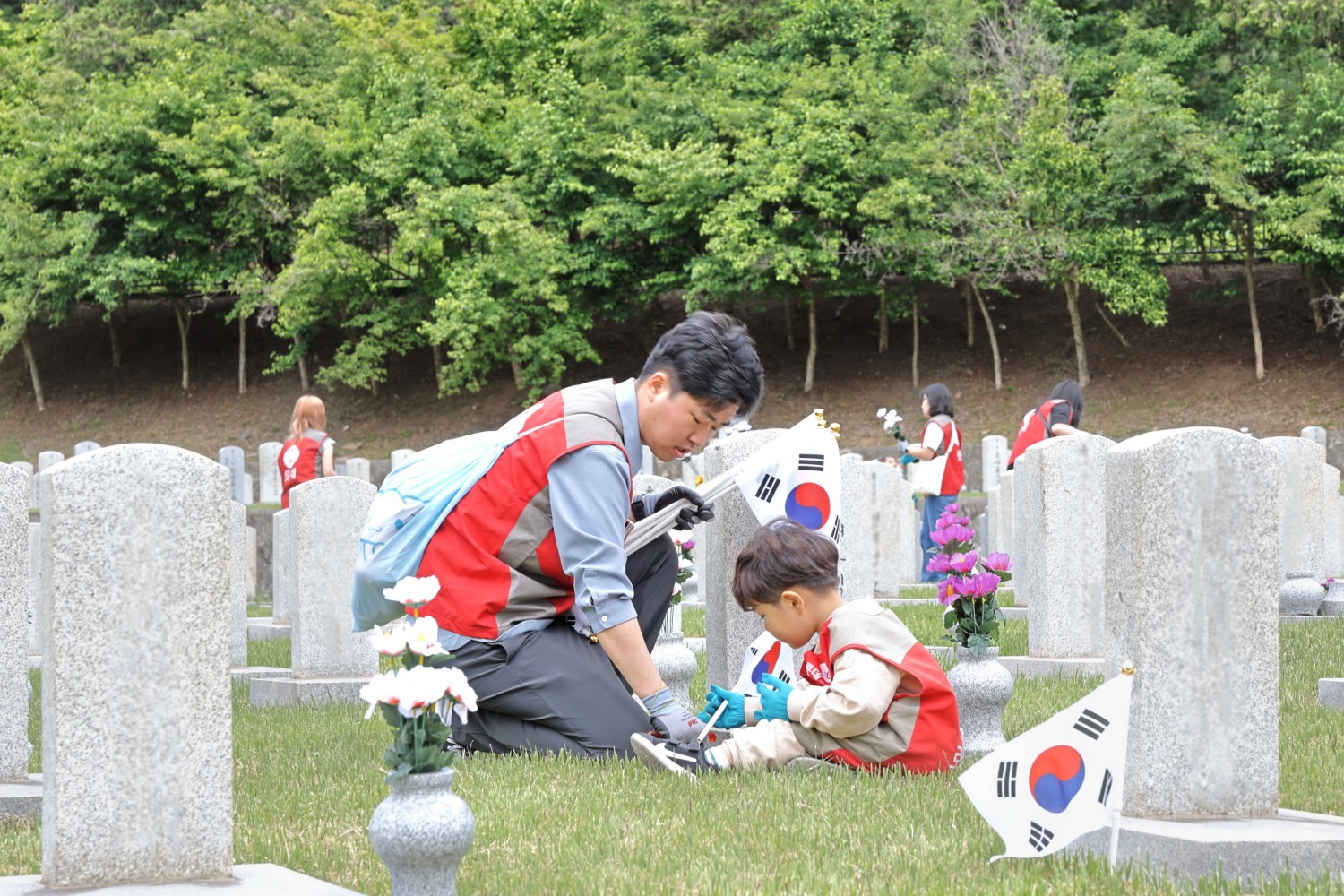 롯데건설 ‘샤롯데 봉사단’이 묘비 옆에 태극기를 꽂고 있다./사진제공=롯데건설