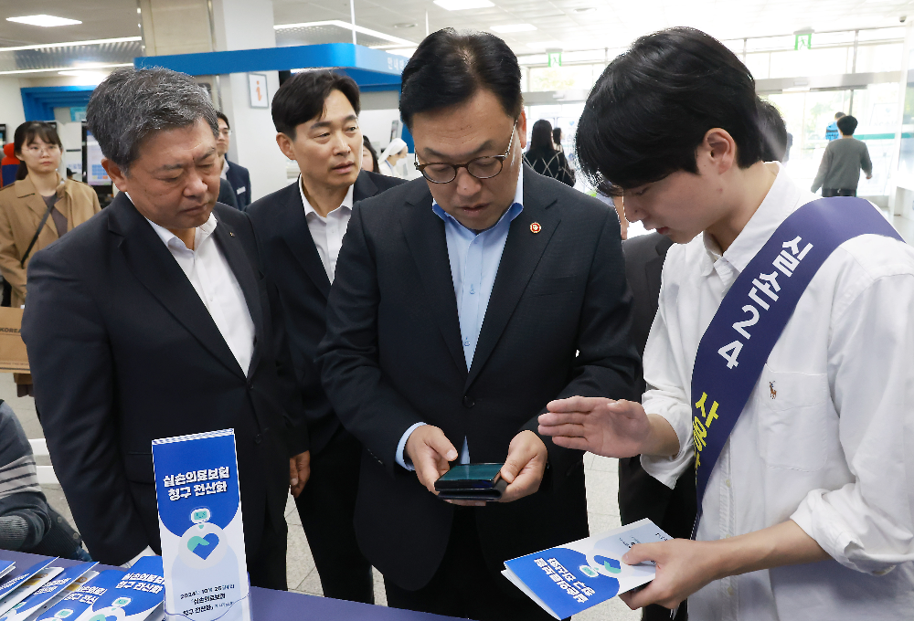 김병환 금융위원장(가운데)이 병원에서 실손보험 청구 전산화 앱 '실손24' 사용법 설명을 듣고 있다./사진=금융위원회
