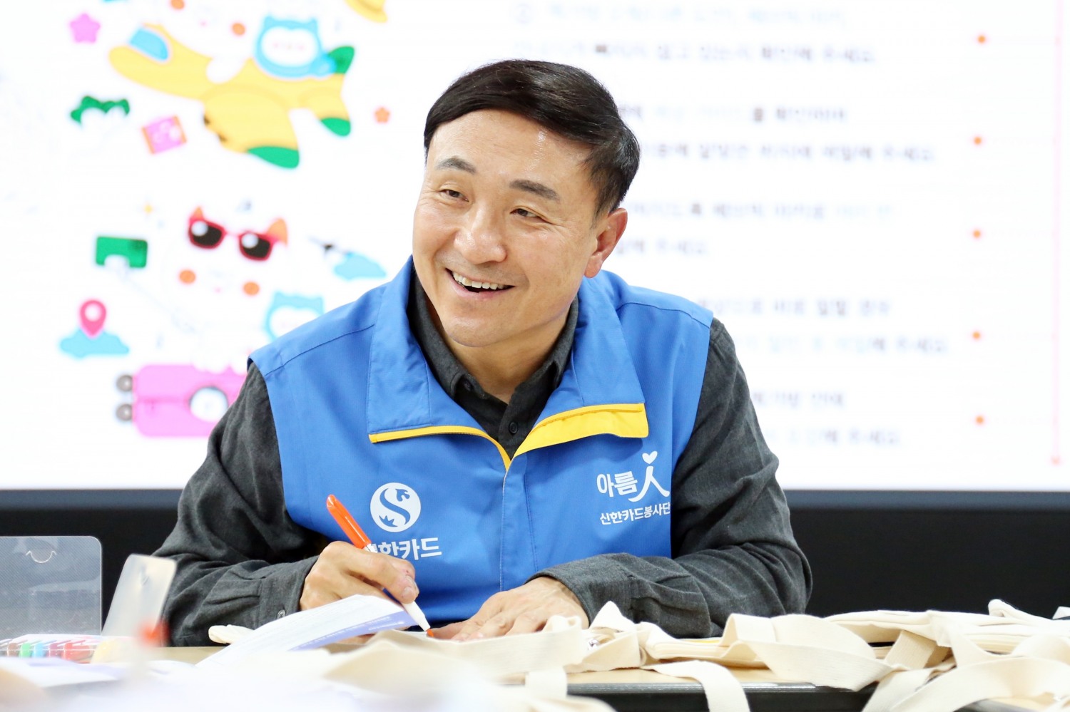 문동권 신한카드 대표가 베트남 및 인도네시아 등 해외법인 진출국의 취약계층 아동을 위한 아름인 책가방 만들기 봉사활동을 진행하고 있다./사진=신한카드