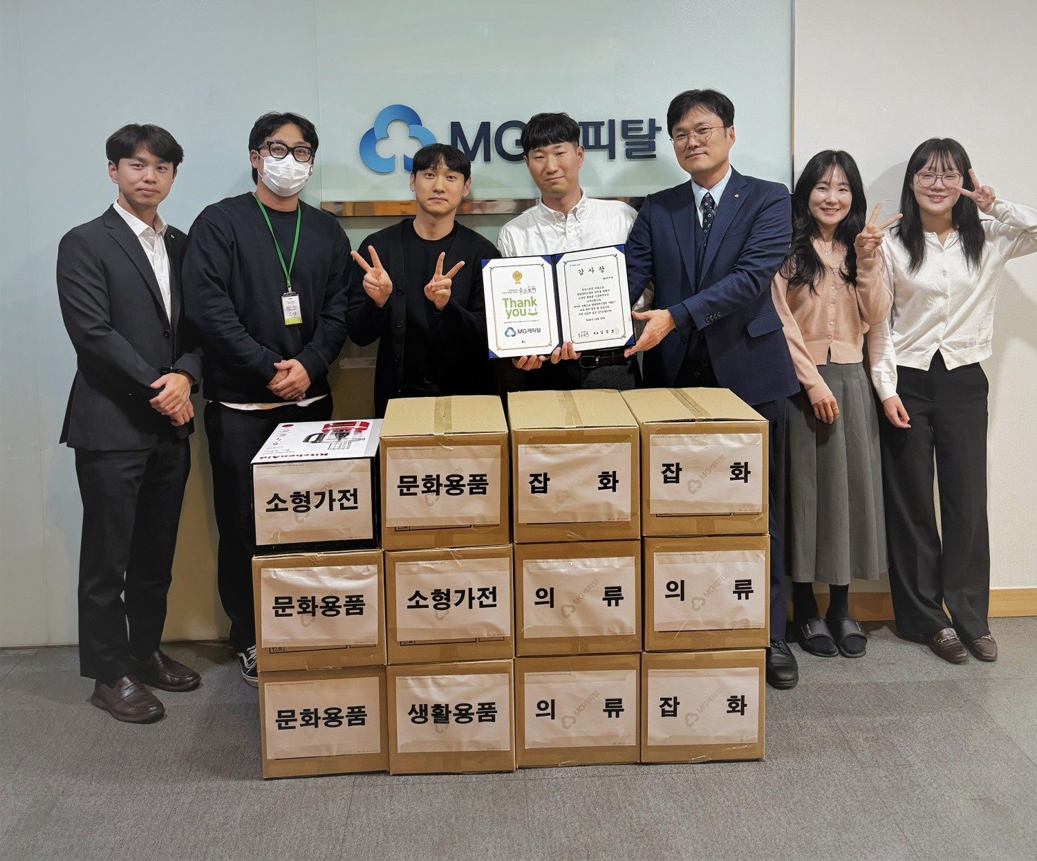 박요한 MG캐피탈 전무(오른쪽에서 세 번째)와 직원들이 최우성 숲스토리 과장(왼쪽에서 두 번째)에게 기부 물품을 전달하고 기념촬영을 하고 있다.(2025.12.08.)/사진 제공 = MG캐피탈