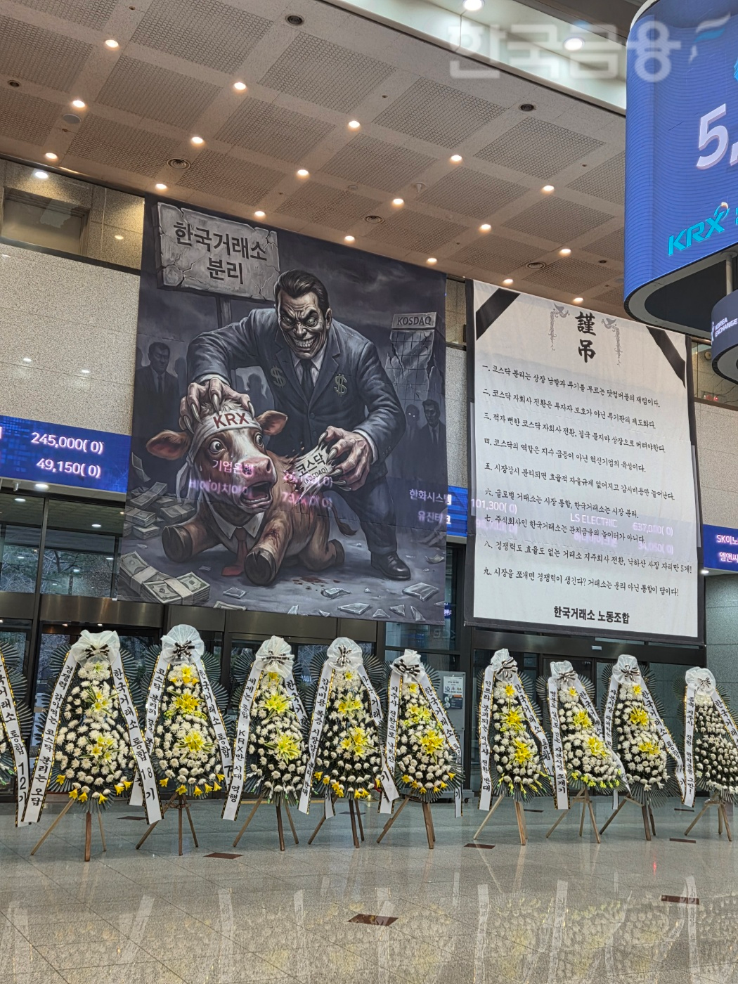 여의도 한국거래소(KRX) 서울 사옥 1층 로비에 거래소 지주사 전환 및 코스닥 시장 분리 방안 추진에 반대하는 노조의 현수막과, 그림, 그리고 근조 화환이 가득 차 있다. / 사진= 한국금융신문(2026.02.11 기준)
