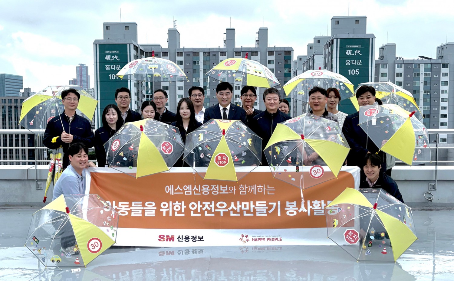공문용 SM신용정보 대표이사(가운데)와 임직원들이 지난 21일 서울 영등포구 본사에서 어린이와 아동의 빗길 교통 안전을 위해 제작한 ‘사랑의 안전우산’을 펼쳐 보이며 기념촬영을 하고 있다. /사진제공=SM그룹