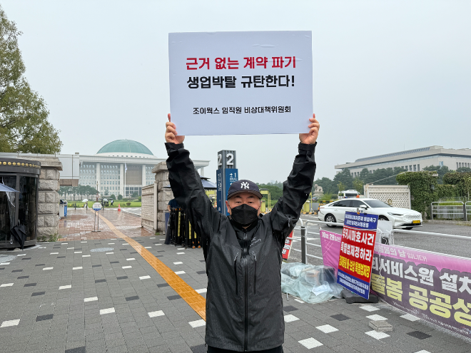 조이웍스 임직원 비상대책위원회 관계자가 20일 서울 여의도 국회 앞에서 호카 국내 총판 계약 파기에 반발하는 피켓을 들고 시위를 하고 있다./사진-조이웍스 비대위