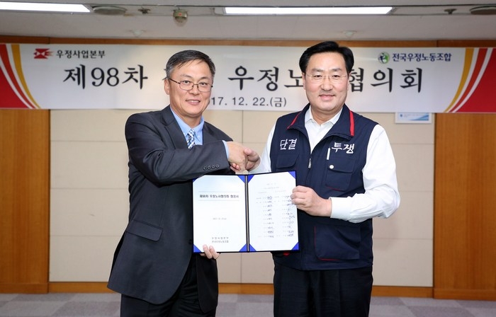 우정사업본부와 전국우정노동조합은 지난 22일 광화문우체국에서 노사협의회를 열고 제도개선, 근로조건 등 총 33개 안건을 합의했다. 강성주 우정사업본부장(왼쪽)과 김명환 위원장이 협정서를 들고 악수를 하고 있다./자료=우정사업본부