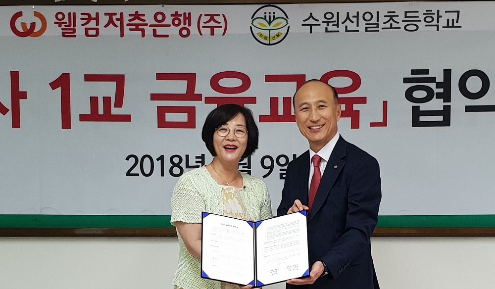 △임경애 수원선일초등학교 교장(왼쪽)과 김대웅 웰컴저축은행 대표가 1사1교 금융협약식 후 기념촬영을 하고 있다./사진=웰컴저축은행