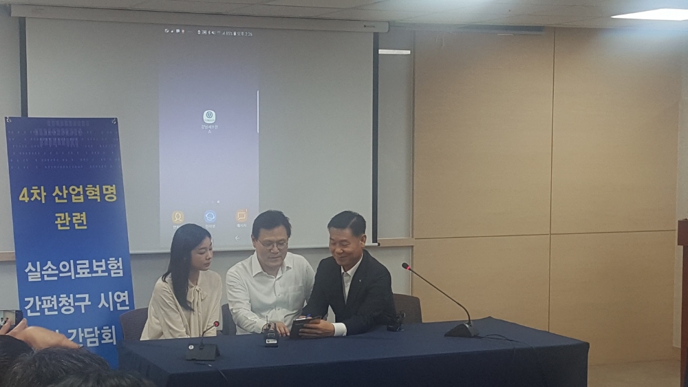 △최종구 금융위원장(가운데)과 김연아 선수(좌측)가 KB손해보험의 실손보험금 간편청구 시스템을 시연해보이고 있다. / 사진=장호성 기자