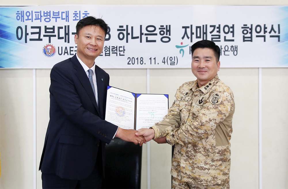 KEB하나은행은 4일 아랍에미리트에 파병되어 있는 대한민국 육군 UAE군사훈련 협력단(아크부대)과 국고금 관리 및 각종 금융서비스 지원을 위한 자매결연을 체결하였다. 자매결연 체결 후 노영준 KEB하나은행 아부다비지점장(사진 왼쪽)과 김현태 UAE군사훈련협력단장(중령)이 기념사진 촬영을 하고 있다. / 사진= KEB하나은행