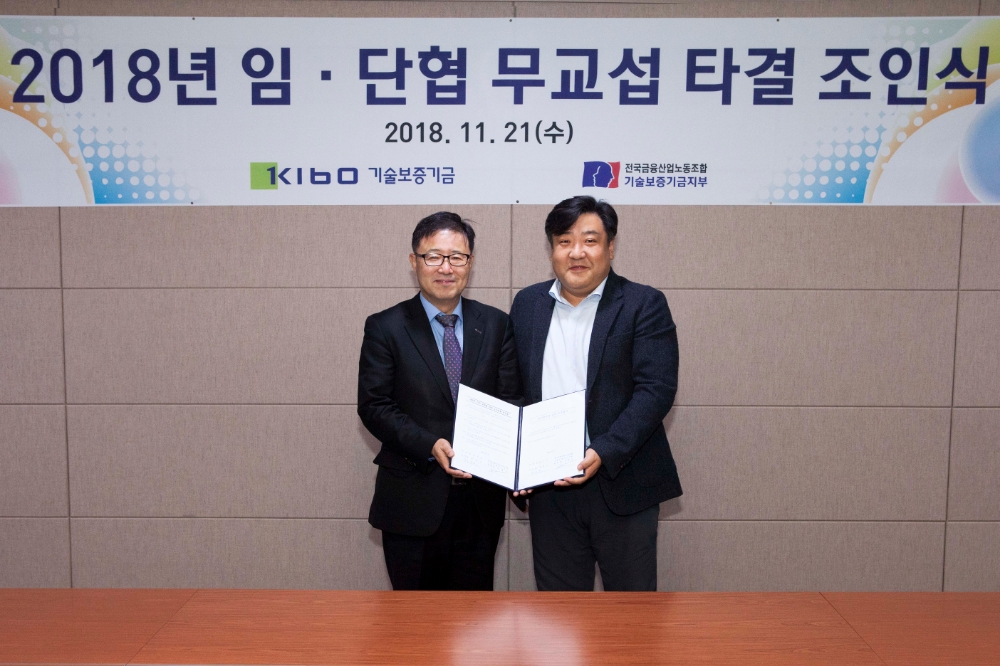 △정윤모 기보 이사장(왼쪽), 김봉근 노조위원장이 임단협 타결 조인식 후 기념촬영을 하고 있다./사진=기술보증기금