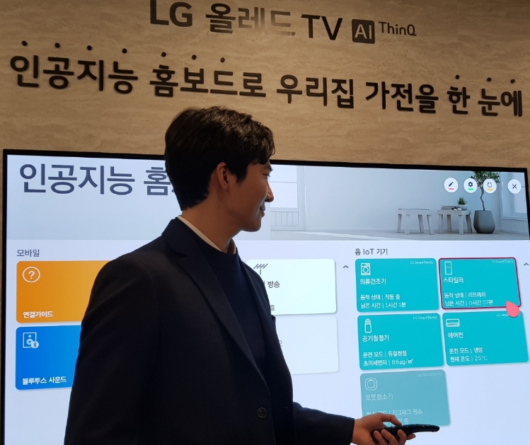 △모델이 인공지능 홈 모드를 리모콘을 활용하여 시연하고 있다. 스타일러의 동작 상황을 확인하고 있는 모습/사진=오승혁 기자