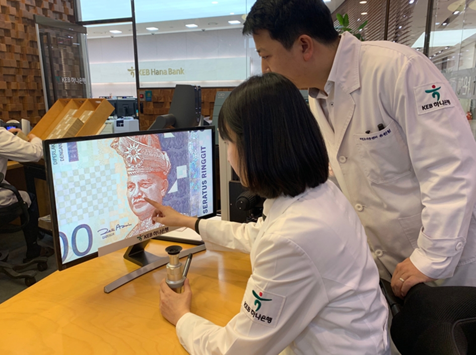 KEB하나은행 위변조대응센터 직원들이 전문장비로 말레이시아 화폐를 감정하고 있다. / 사진= KEB하나은행