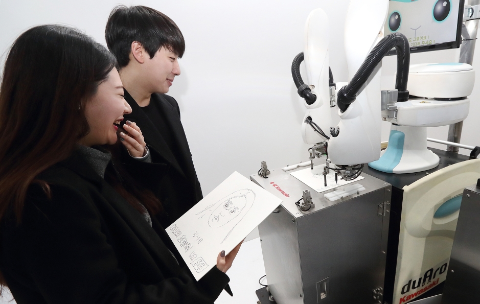 △KT 홍보모델들이 초상화 로봇을 체험해보고 있다/사진=KT