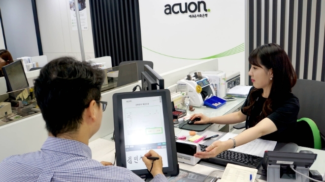 ▲고객이 애큐온저축은행의 한 영업점에서 새로 도입된 전자서식 서류에 서명하고 있다./ 사진=애큐온저축은행