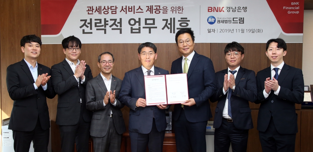 김백용 경남은행 상무(오른쪽 네번째)가 본점을 방문한 관세법인 드림 영남지사 신성훈 관세사(오른쪽 세번째)와 ‘관세법인 업무 협약식’을 체결하고 있다./사진=경남은행