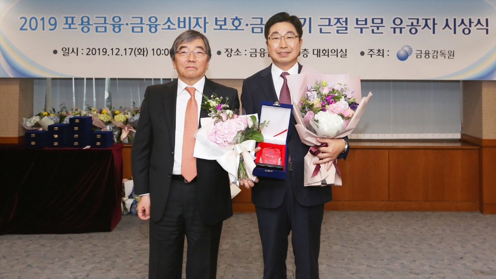 황윤철 경남은행장(오른쪽)이 ‘2019 포용금융·금융소비자 보호·금융사기 근절 부문 유공자 시상식’에 참석해 윤석헌 원장으로부터 서민금융 우수상 기관 표창을 받고 있다./사진=경남은행