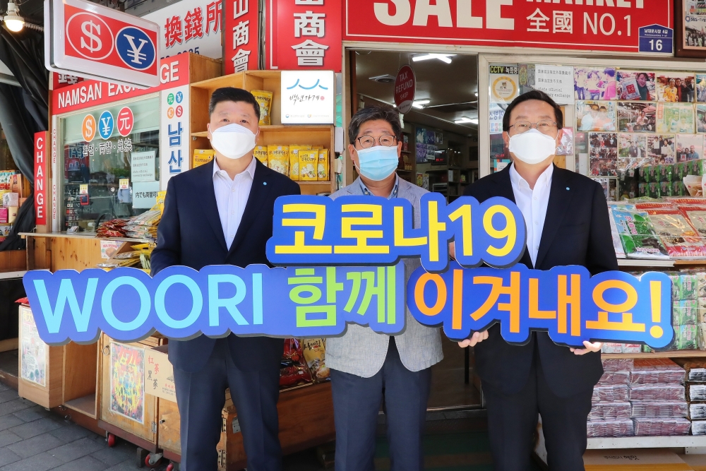 손태승 우리금융그룹 회장(사진 오른쪽)과 권광석 우리은행장(사진 왼쪽)이 서울 중구 소재 남대문시장에서 물품구매 후 박칠복 남대문시장 남산상회 대표와 코로나19 극복을 다짐하며 기념촬영을 하고 있다. / 사진= 우리금융지주