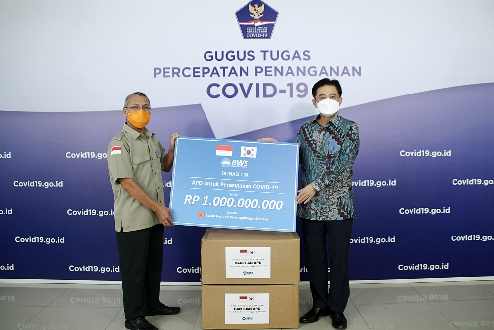 우리소다라은행은 인도네시아 자카르타의 국가재난방지청에 방호복 5000벌을 기부했다. 최정훈 우리소다라은행 법인장(사진 오른쪽)과 인도네시아 국가재난방지청 이브누(Ibnu)국장이 기념촬영을 하고 있다. / 사진= 우리은행(2020.05)