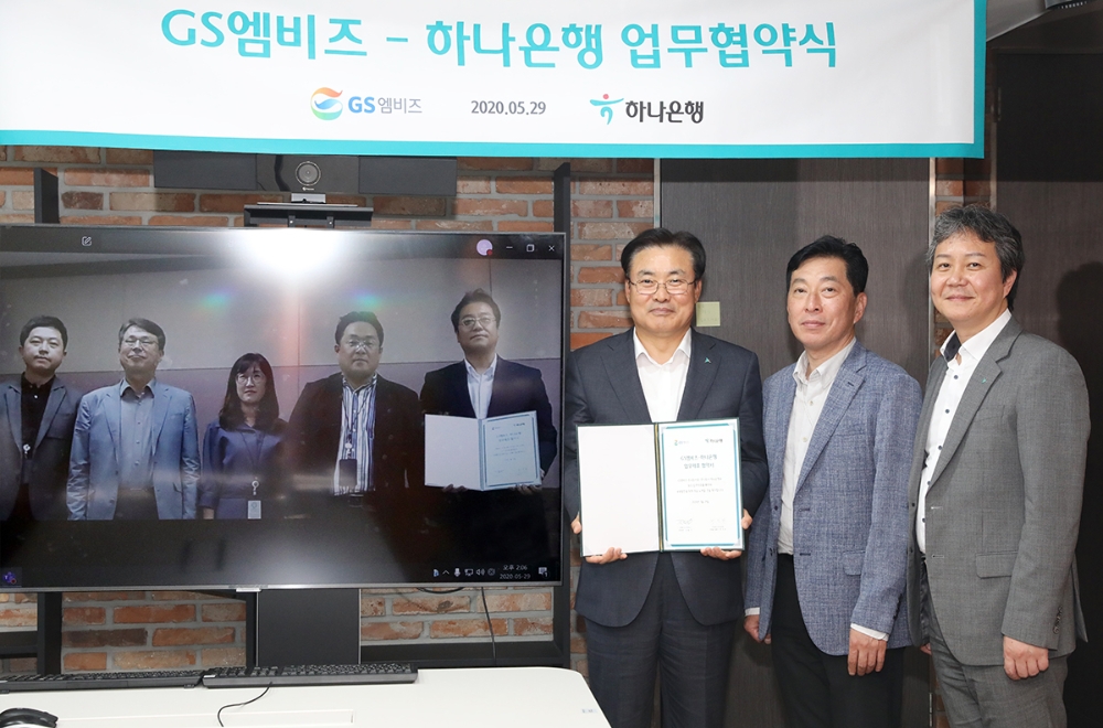 하나은행이 29일 자동차 종합 서비스 기업 GS엠비즈와 '자동차 생활 금융서비스'를 위한 전략적 업무 협약을 체결했다. 정석화 하나은행 리테일그룹장(사진 오른쪽에서 세번째)이 서울 중구 을지로 소재 하나은행 본점에서 김철민 GS엠비즈 전무(사진 오른쪽에서 네번째)와 화상 영상을 통해 업무 협약 체결 후 기념사진 촬영을 하고 있다. / 사진= 하나은행(2020.05.31)