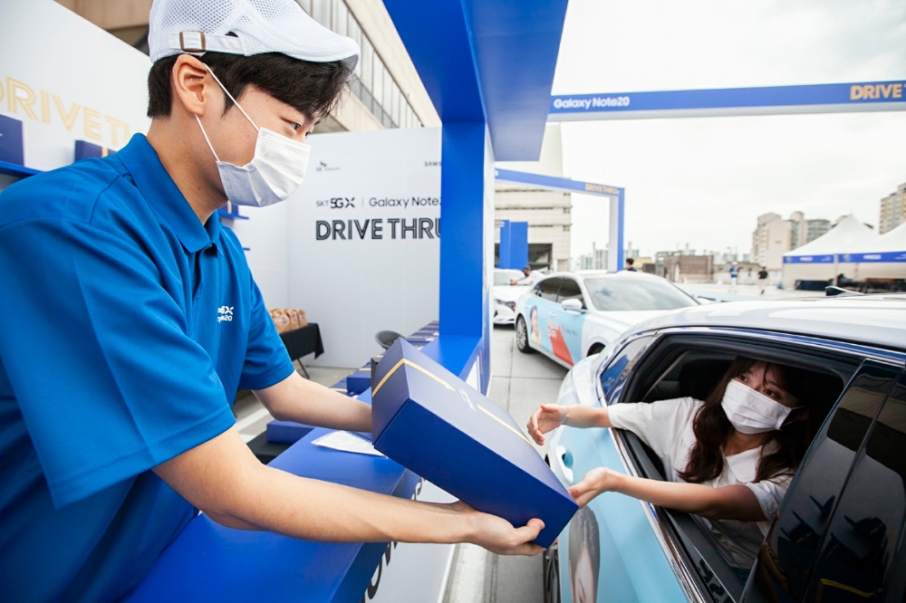 SK텔레콤 홍보모델들이 서울 성동구에 위치한 복합 쇼핑몰 왕십리 비트플렉스 5층 야외 주차장에서 노트20 드라이브 스루 서비스를 소개하고 있다. 이날 20여명의 일반 고객은 자택에서 SK텔레콤이 마련한 T맵 택시를 타고 현장에 온 다음 본인의 노트20을 안전하게 수령했다./사진=SK텔레콤