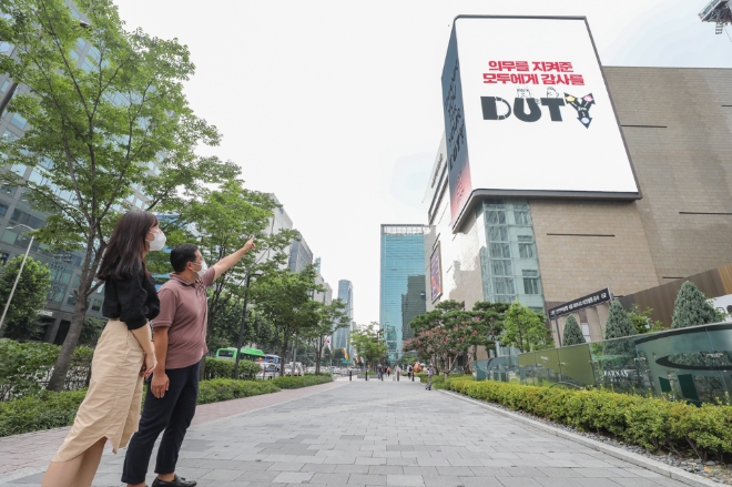 현대백화점면세점은 오늘(24일)부터 무역센터점 외벽에 설치된 농구장 3개 크기의 초대형 디지털 사이니지에 신종 코로나바이러스 감염증(코로나19) 극복을 위한 응원 영상인 '땡큐 포 유어 듀티(Thank you for your DUTY)'를 상영한다. 사진=현대백화점그룹.