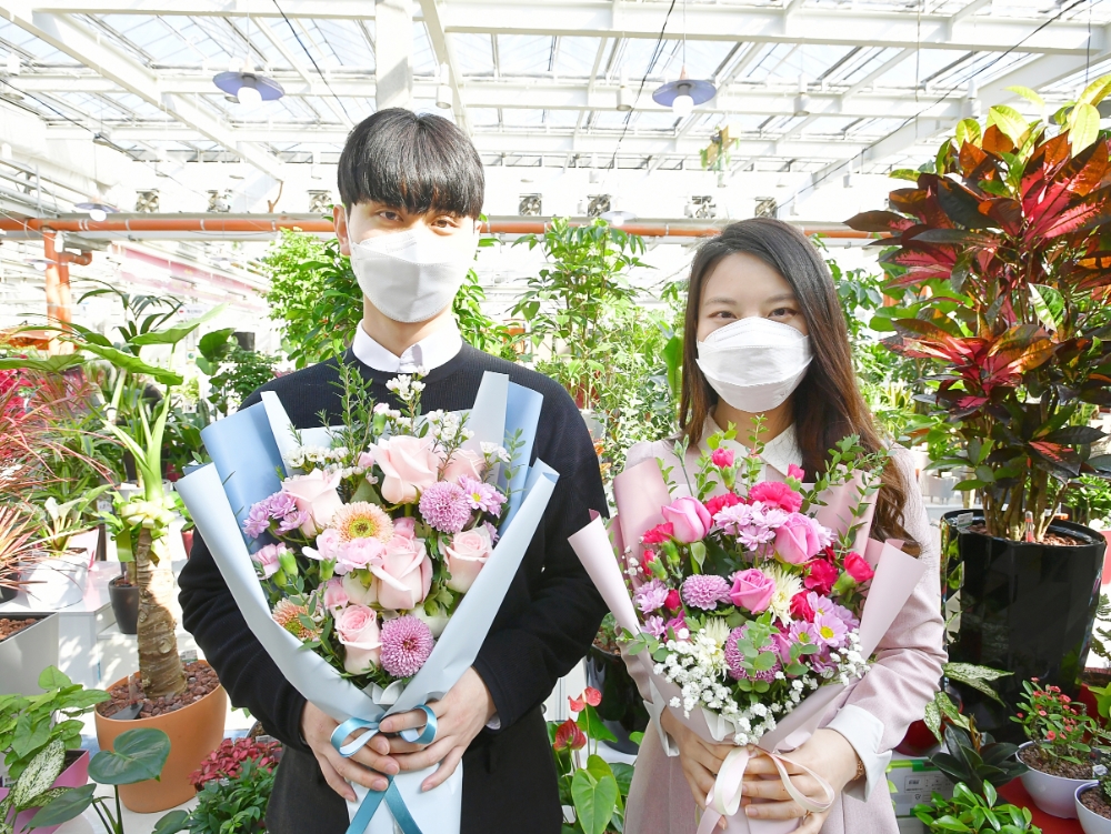 농협은행 디지털마케팅부 황재웅 계장(왼쪽)과 염유진 계장이 한국화훼농협에서 만드는 ‘희망꽃다발’을 들고 기념사진을 촬영하고 있다. /사진=NH농협은행 제공