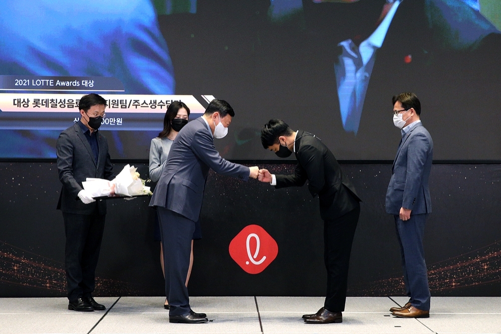 롯데는 23일 서울 잠실 롯데월드타워 스카이31 컨퍼런스A홀에서 그룹 브랜드 가치 상승에 기여한 팀을 선정하는 ‘2021 롯데 어워즈’ 시상식을 진행했다. 사진은 롯데 신동빈 회장이 대상을 수상한 롯데칠성음료 생수지원팀 박원 매니저(오른쪽에서 두 번째)와 주먹 인사를 하며 격려하고 있다./ 사진제공 = 롯데