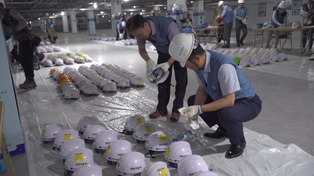 포스코건설 직원들이 협력사 근로자들의 안전모 클리닝 작업을 하고 있다. / 사진=포스코건설