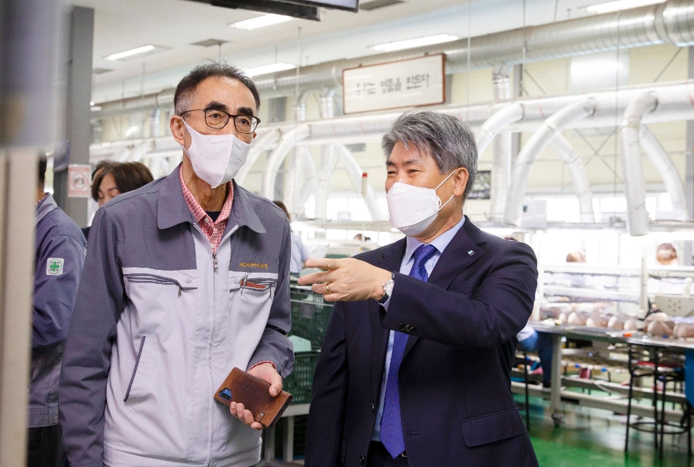 윤종원 기업은행장(오른쪽)이 지난 12일 부산 사하구에 위치한 친환경 소재 신발 제조업체 노바인터내쇼널을 방문해 이효 대표와 생산공정에 대해 대화를 나누고 있다./사진=IBK기업은행