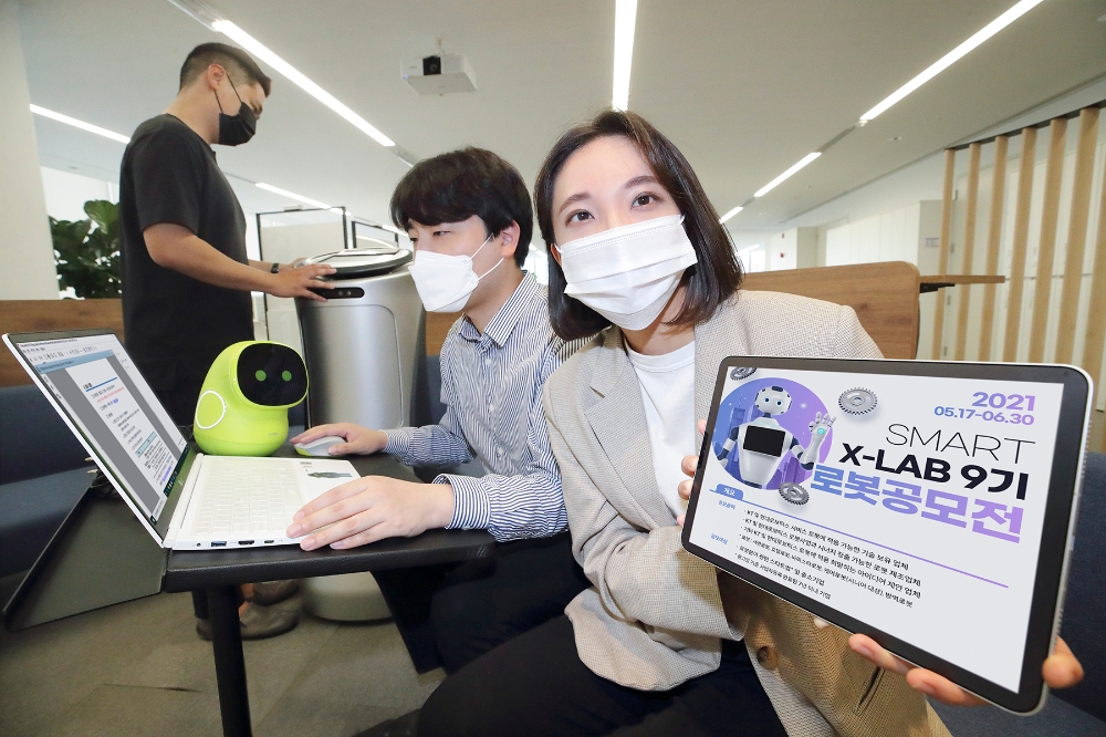 KT 직원들이 로봇 우수기업 선발 공모전 포스터를 확인하고 있다. 사진=KT