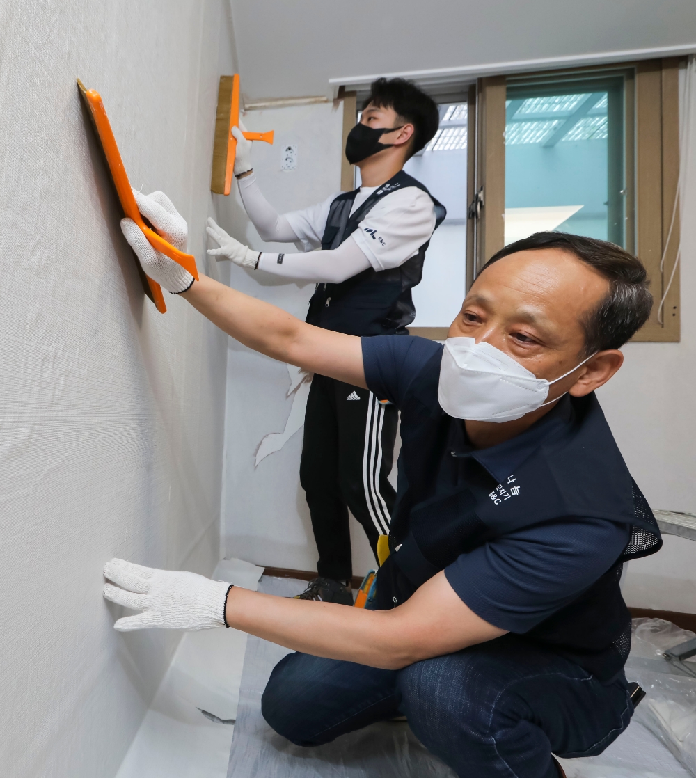 이규성 DL이앤씨 주택사업 본부장(앞)과 직원이 서울시 종로구에 위치한 선덕원에서 벽지 시공을 하고 있다. / 사진=DL이앤씨