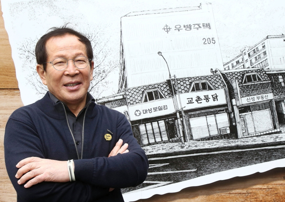 교촌에프앤비㈜ 창업주 권원강 前 회장이 교촌치킨 1호점 일러스트 앞에서 사진 촬영을 하고 있다. / 사진제공 = 교촌에프앤비㈜